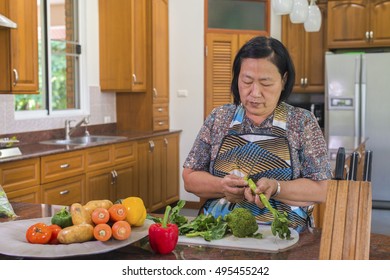 Senior Asian Woman Cutting Kale Vegetable.