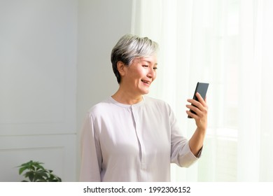 Senior Asian Woman Holding Cell Phone Using Mobile Online Apps.