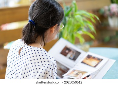 Senior Asian Woman Looking At Photo Album To Remind Of Old Happy Memmory