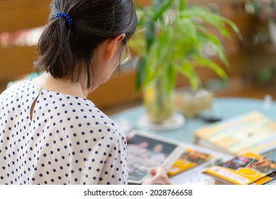 Senior Asian Woman Looking At Photo Album To Remind Of Old Happy Memmory