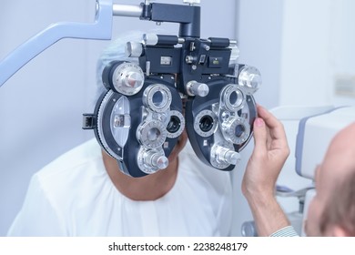 Senior Asian woman looking through optical phoropter during eye exam, diagnostic ophthalmology equipment, selective focus - Shutterstock ID 2238248179