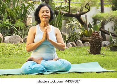 Senior Asian Woman Meditating As Part Of Yoga Training