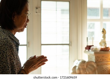 Senior Asian Woman Is Praying To The Buddhist Goddess Of Mercy Or Quan Yin In The House. Religion And Culture Concept