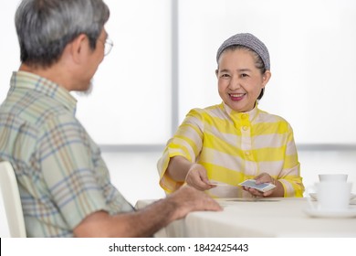 Senior Asian Woman Smile With Happy Face While Playing Card Game With Her Friend, Concept For Happiness And Hobby In Free Time Of Older People.