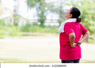 Senior Asian Woman Suffering From Backache While Exercise On Park Outdoors. Mature Woman With Backache,Lower Back Pain. People ,health Care Or Medical And Lifestyle Concept