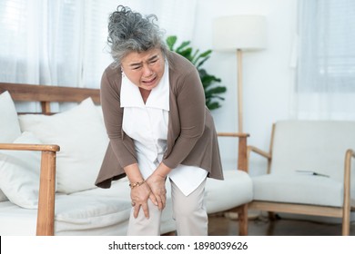 Senior Asian Woman Suffering From Knee Pain At Home.