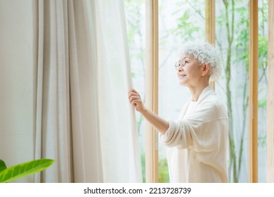 Senior Asian Woman Sun Bathing In The Living Room