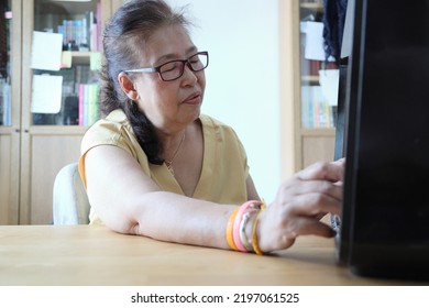 The Senior Asian Woman Trying To Listen Music From The Vintage Radio.