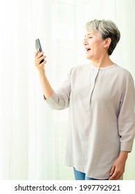 Senior Asian Woman Using Or Talking On Her Mobile Phone.