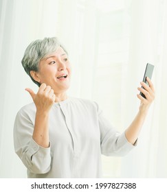 Senior Asian Woman Using Or Talking On Her Mobile Phone.