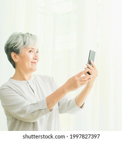 Senior Asian Woman Using Or Talking On Her Mobile Phone.