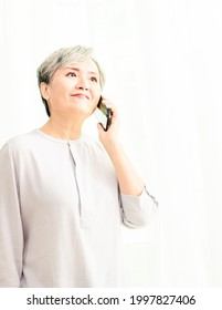 Senior Asian Woman Using Or Talking On Her Mobile Phone.