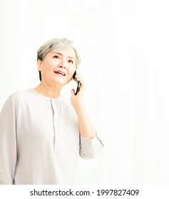 Senior Asian Woman Using Or Talking On Her Mobile Phone.