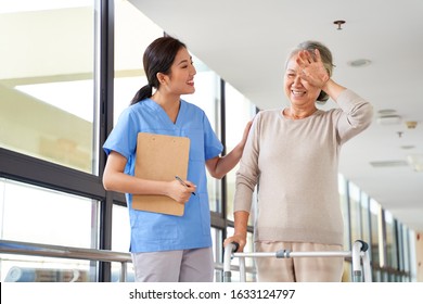 Senior Asian Woman Wiping Off Sweat From Forehead During Physical Therapy Session In Rehab Center