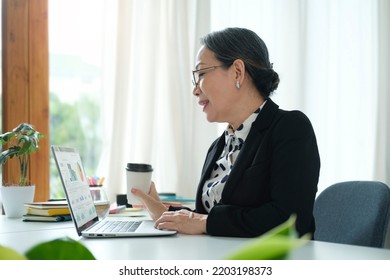 Senior Asian Woman Working From Home With Laptop And Smart Phone. Old Woman Living And Learning Online.