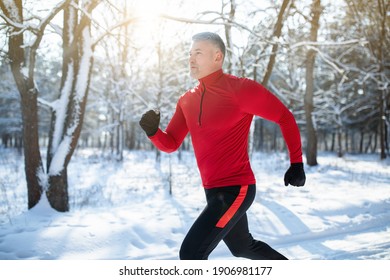 Senior Athletic Man In Sportswear Running At Winter Park, Copy Space. Mature Male Runner Training Outdoors, Jogging In Nature. Seasonal Outdoor Sports And Cold Tempering Concept