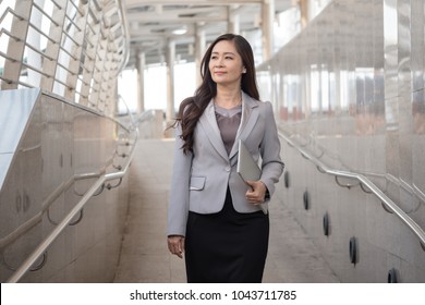 Senior Attractive Business Woman With Laptop Walking On City Street.