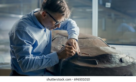 Senior Automotive Designer With Rake Sculpts Futuristic  Car Model From Plasticine Clay. He Works In A Special Studio Located In A Large Car Factory.