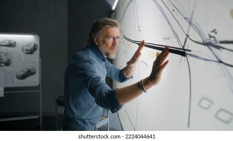 Senior automotive male designer creating sketch with duct tape on paper whiteboard, developing futuristic electric car future design. He working in modern car design development studio. - Powered by Shutterstock