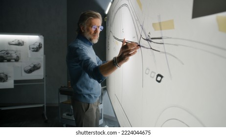 Senior automotive male designer creating sketch with duct tape on paper whiteboard, developing futuristic electric car future design. He working in modern car design development studio. - Powered by Shutterstock