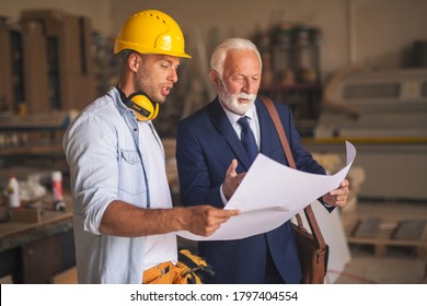 Senior bearded businessman is pointing hand at the blueprint asking a contractor to explain him some details he does not fully understand. - Powered by Shutterstock