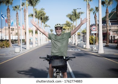 Senior Bearded Man Enjoying Cycling In The Deserted Street Under The Sun In Tenerife, Happy Lifestyle With Retired People