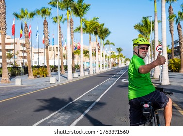 Senior Bearded Man Enjoying Cycling In The Deserted Street Under The Sun In Tenerife, Happy Lifestyle With Retired People