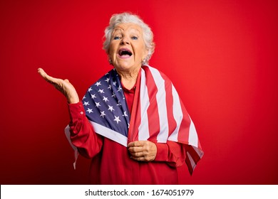 Senior beautiful grey-haired patriotic woman wearing united states flag over red background very happy and excited, winner expression celebrating victory screaming with big smile and raised hands - Powered by Shutterstock