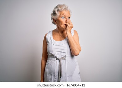 Senior Beautiful Grey-haired Woman Wearing Casual Summer Dress Over White Background Looking Stressed And Nervous With Hands On Mouth Biting Nails. Anxiety Problem.