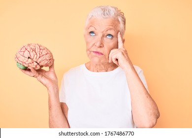 Senior beautiful woman with blue eyes and grey hair holding brain as mental health concept serious face thinking about question with hand on chin, thoughtful about confusing idea  - Shutterstock ID 1767486770