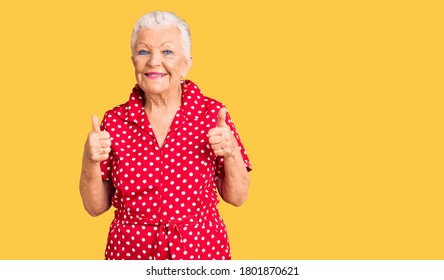 Senior beautiful woman with blue eyes and grey hair wearing a red summer dress success sign doing positive gesture with hand, thumbs up smiling and happy. cheerful expression and winner gesture.  - Shutterstock ID 1801870621
