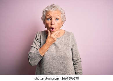 Senior Beautiful Woman Wearing Casual T-shirt Standing Over Isolated Pink Background Looking Fascinated With Disbelief, Surprise And Amazed Expression With Hands On Chin