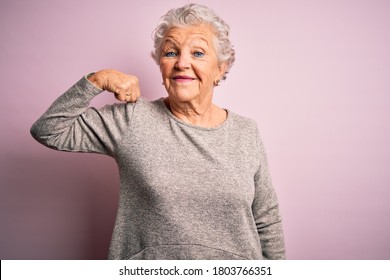 Senior beautiful woman wearing casual t-shirt standing over isolated pink background Strong person showing arm muscle, confident and proud of power