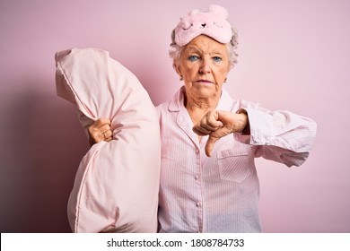 Senior Beautiful Woman Wearing Sleep Mask Holding Pillow Over Isolated Pink Background With Angry Face, Negative Sign Showing Dislike With Thumbs Down, Rejection Concept