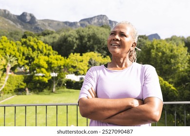 A senior biracial woman smiles confidently outdoors, copy space. Her grey dreadlocks and light purple shirt stand out against green background, unaltered - Powered by Shutterstock