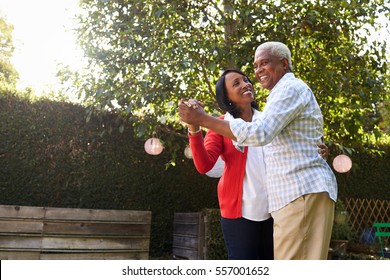 Senior black couple dancing in their back garden