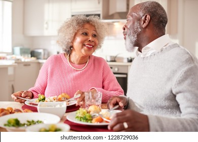 Senior black couple smiling to each other as they eat Sunday dinner together at home, close up