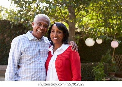 Senior black couple in their garden looking to camera