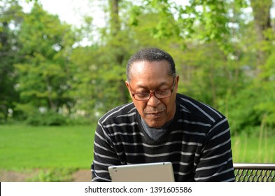 A Senior Black Man Enjoys A Beautiful Day At The Park Watching Movies On His Tablet, Taking In Leisurely Exercise, And Calling Longtime Friends For Humorous Conversation 