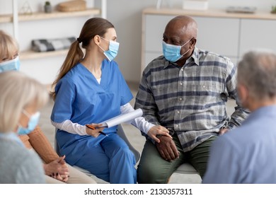 Senior Black Man Getting Psychological Support From Female Therapist At Nursing Home, Doctor Holding His Hand And Looking Into Eyes, Wearing Protective Face Masks, Healthy Aging Program Concept