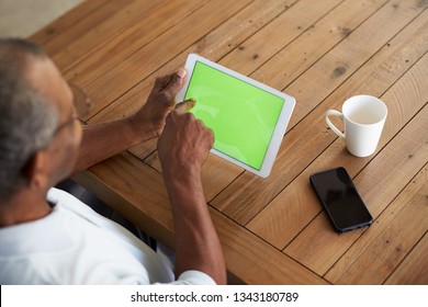 Senior black man sitzt am Tisch mit Tablet-Computer, erhöht über Schulter
