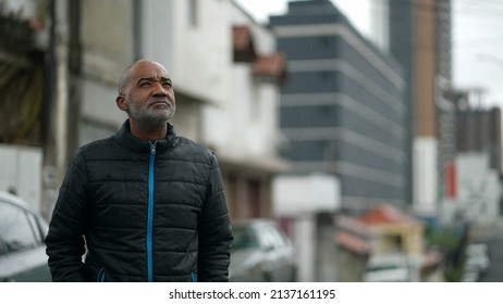 A Senior Black Man Standing Outside In The Rain Looking At Sky Drizzle