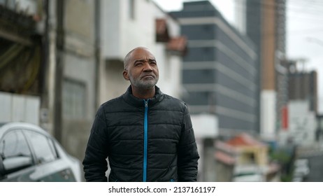 A Senior Black Man Standing Outside In The Rain Looking At Sky Drizzle