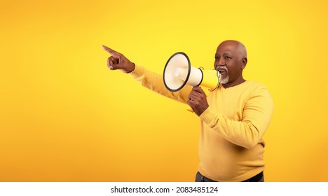 Senior Black Man Yelling Into Megaphone, Announcing News Or Message, Pointing At Blank Space On Orange Background, Banner Design. Elderly African American Male Screaming With Loudspeaker