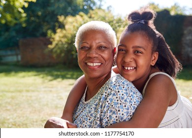 Senior black woman and granddaughter sit embracing outside