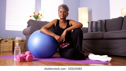 Senior Black Woman Sitting On Floor With Exercise Equipment