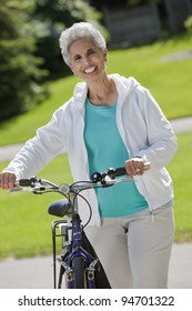 Senior Black Woman Walking Her Bike Through The Park