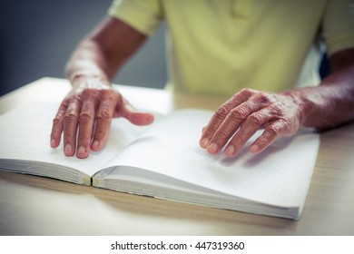 Senior blind man reading a braille book at home - Powered by Shutterstock