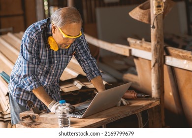 Senior Builder Wood Worker Using Laptop Computer At Aiding Design At Construction Work.