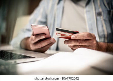 Senior Business Man Checking His Finance On Credit Card. Close Up. Focus Is On Hand.